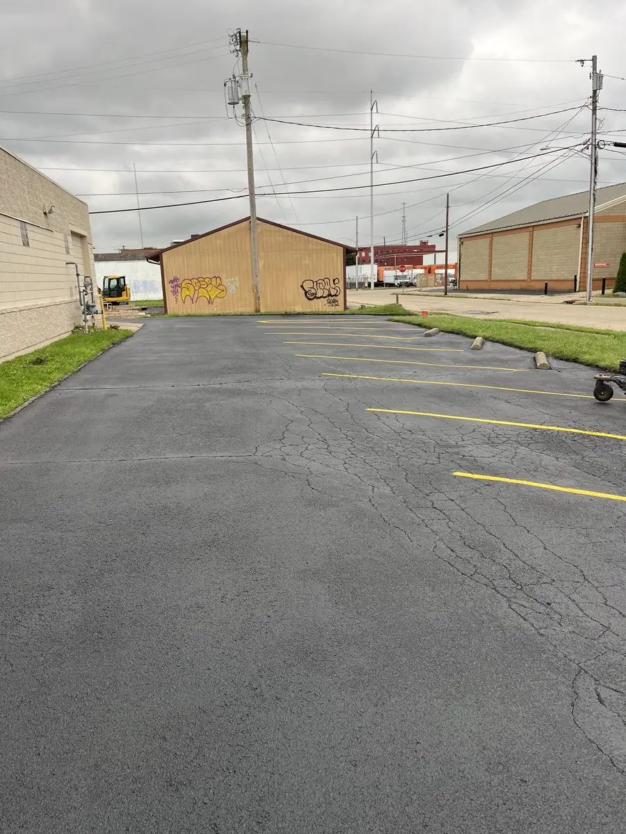 The same parking lot after sealcoating, with a uniform surface and fresh yellow stall striping